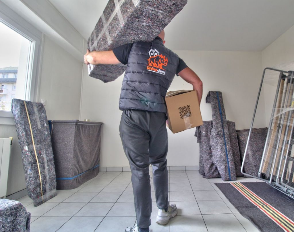 Un de nos déménageurs Rhinodem porte un meuble et un carton lors d'un déménagement à Nancy