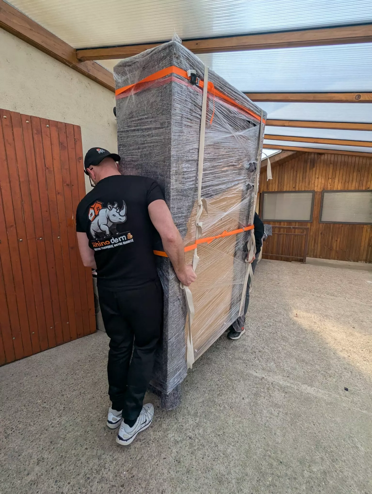 Deux déménageurs portent une armoire