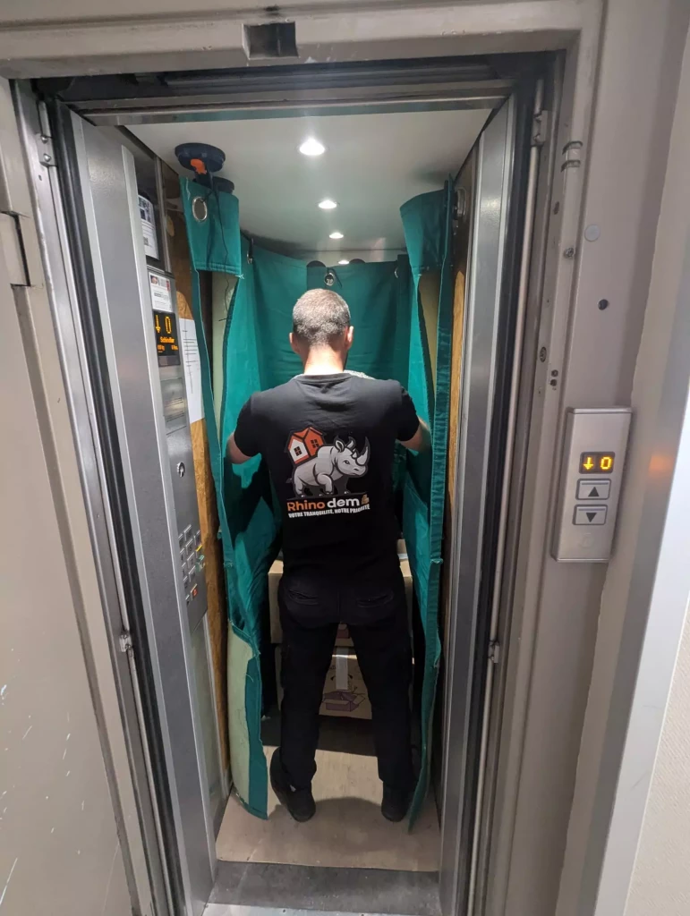 Un déménageur protège un ascenseur avec des housses