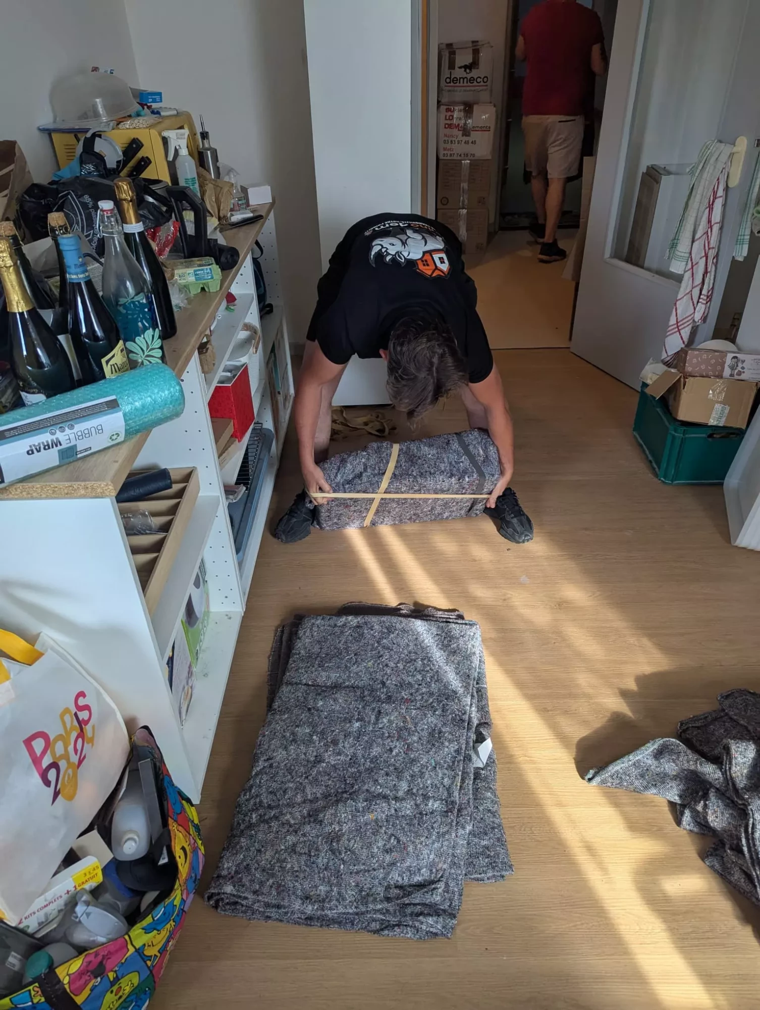 Un déménageur emballe un meuble avec une couverture de déménagement